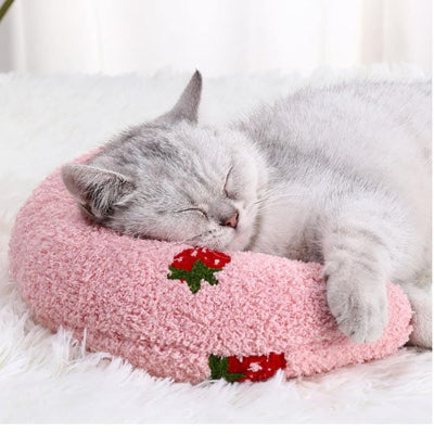 félin dormant profondément sur son coussin banane pour chat rose